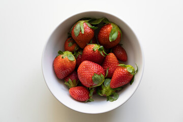 Top view of fresh strawberries in a white bowl isolated