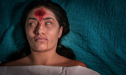 Woman dressed as a zombie for halloween with chilling gunshot wound to the forehead