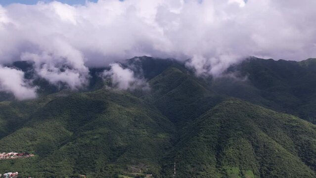 Drone hyperlapse of a green mountain full of low moving clouds