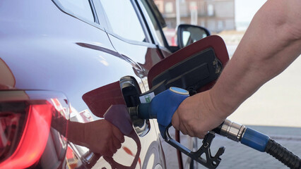 Man filling gasoline in car at gas station. Fuel injector is inserted into the vehicle's gas tank at a petrol station. Refueling car by a person at a gas station. Transportation concept