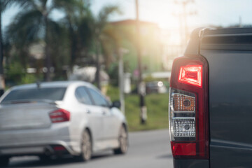 Rear side of pick up car gray color stops on the road with turn on brake light. background and blurred of other cars stop in the city at days.