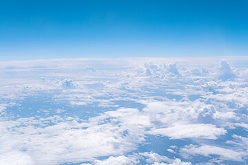 Aerial view from airplane window. Above clouds. Blue sky and many clouds background with copy space.
