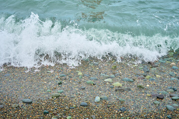 Sea shore with pebbles, wet sea pebbles on the beach and quiet sea surf. Restless sea and waves. Soft focus