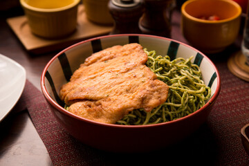 Green sauce pesto spaguetti noodles pasta with breaded chicken filet Peruvian comfort restaurant gourmet food