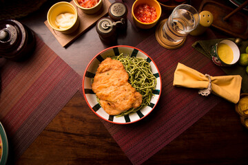 Green sauce pesto spaguetti noodles pasta with breaded chicken filet Peruvian comfort restaurant gourmet food
