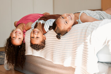 Fun, playful and silly kids lying on a bed with cute hairstyle and smiling portrait. Little...