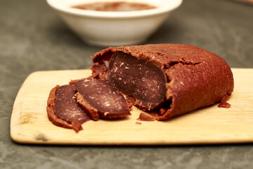 basturma on a wooden cutting board next to a plate with spices
