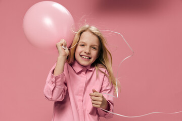 horizontal portrait of a cute beautiful, happy girl with a pink balloon in a pink dress on a pink background with an empty space for an advertising tex