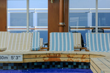 Sun loungers at indoor pool solarium of ocean liner cruiseship cruise ship with patterned cushions...