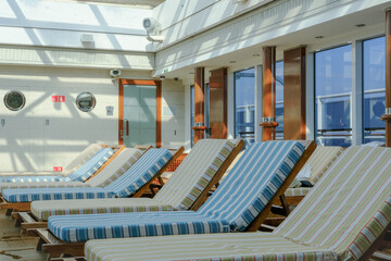 Sun loungers at indoor pool solarium of ocean liner cruiseship cruise ship with patterned cushions...