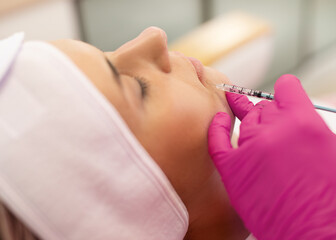 Side view of young woman getting beauty collagen injection. Cosmetologist making anti-wrinkle...