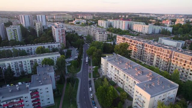 Aerial backwards shot of road between large residential district with high-rise apartment blocks at sunset - Krakow,Poland