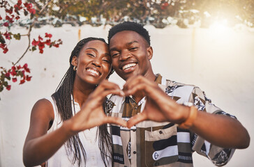 Happy couple heart love sign with their hands posing for a picture or photo while on vacation or...