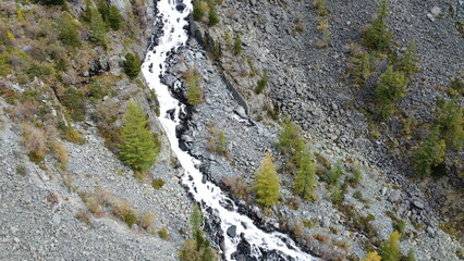 Mountain flowing stream and waterfall in the forest. Picturesque aerial drone landscape view. Altai mountains, Russia