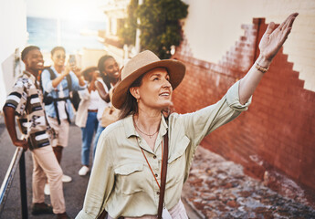 Travel, education and a teacher with students on school field trip, on urban tour. Woman, city guide and group of happy tourists, pointing at local architecture and learning on international holiday. - obrazy, fototapety, plakaty