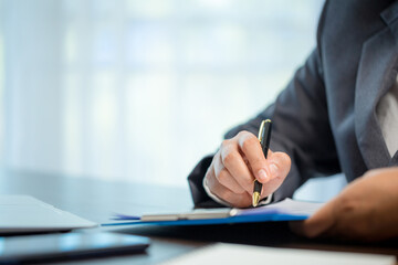 Workplace closeup person professional businesswoman sitting at desk hold pen signing or signature contract paper. Employee woman writing agreement document on paperwork form corporate at work office