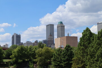 city skyscrapers behind trees with clouds