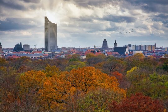 Leipzig Herbstlandschaft Stadtpanorama - Gebäude, Skylines, Hochhäuser während des Sonnenuntergang und die Sonne scheint hinter dem MDR Tower City Hochhaus, daneben das Völkerschlachtdenkmal