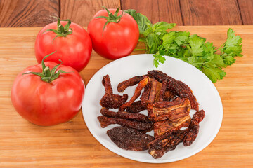 Sun-dried tomatoes on dish against the fresh tomatoes