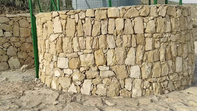 Stone wall texture background natural color. Detail of a stone wall with different sizes of rocks. Unshaped stone wall pattern, a wall made of rocks. Morocco