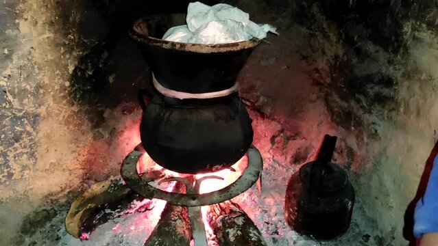 Moroccan couscous cooking on a couscoussier steamer (called a kiskis ) to steam it
on a wooden fire in a fireplace, smoke and flame surround the pot. Traditional plate. Morocco.