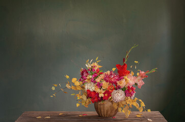 autumn bouquet with red and yellow flowers in ceramic vase on dark background