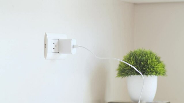 Person plugging a phone charger into the wall plug