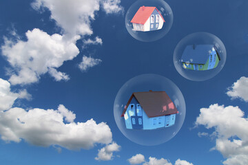 Symbolbild Immobilienblase: Seifenblasen mit Einfamilienhäusern vor einem blauen Himmel