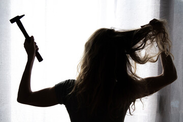 silhouette of woman with hammer screaming hysterical and depressive ready to hit. domestic violence...