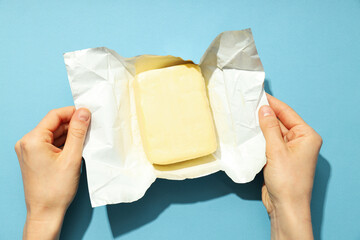 Female hands open package with butter on blue background