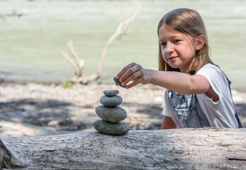 Child building a stone castle on the river. Meditation and relaxation. Zen stone. Image with selective focus