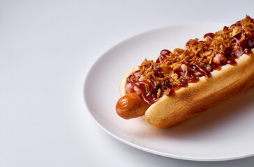 hot dog with barbecue sauce on a white background, white plate