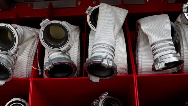Rolled fire hoses, arranged in rows, in the glove compartment of the fire truck