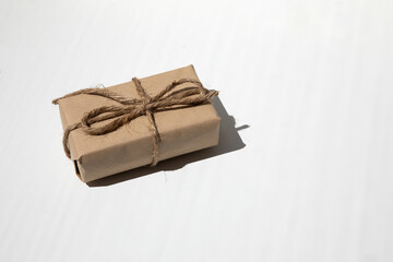 The gift is wrapped in kraft paper and tied with twine on a white background. Top view