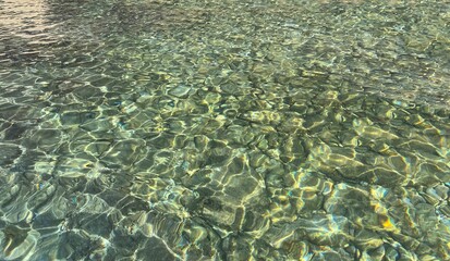 Sea clear transparent water surface with smooth pebbles, stones, gravel at the bottom for zen, relax, mediation, harmony.