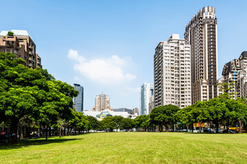 Low-angle view of park green space and modern buildings on both sides in downtown Taichung, Taiwan. here is near the National Taichung Theater.