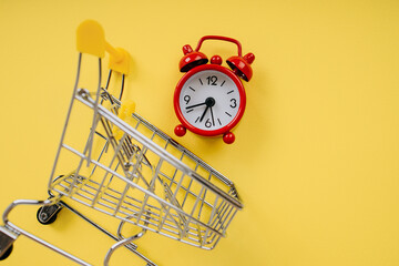 Alarm clock and shopping cart close-up. Shopping time concept