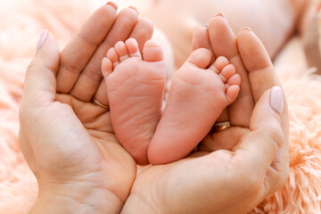 Baby feet in mother's hands. Tiny feet newborn baby on a female hand shape close-up. Mom and her child. Happy family concept. Beautiful concept image of motherhood