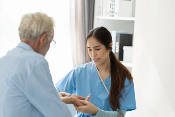 Young female nurse caring senior man sitting in room at hospital. Caring Asian nurse taking care of elderly man in room at nursing home. People and health care concept