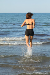 slender athletic young girl running barefoot on the seashore