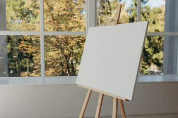 Wooden easel with white canvas. Place for text