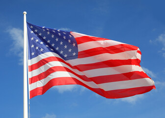 Waving big flag of United States of America on blue sky