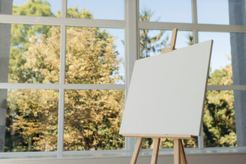 Wooden easel with white canvas. Place for text