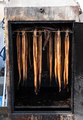 smoked eel hang in a smoker ready to be sold and eaten