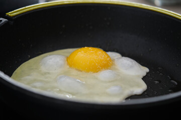 Frying egg in olive oil in a cooking pan.