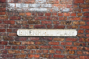 Faded street name sign for Linenhall Place mounted on a red brick wall