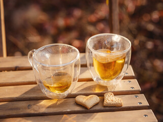 Drinking tea with cookies on wooden table. Cozy autumn mood scene in autumn park