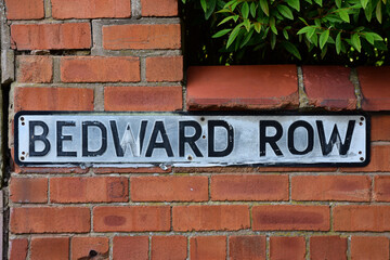 Faded street name sign for Bedward Row mounted on a red brick wall