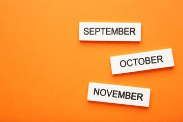 Wooden cubic of september, october, november on orange background. Autumn month.