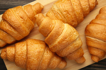 Freshly baked croissants on wooden cutting board,